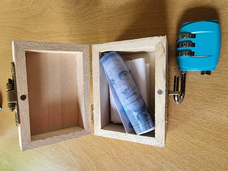 Een open houten kistje met een opgerold briefje en een blauw cijferslot
