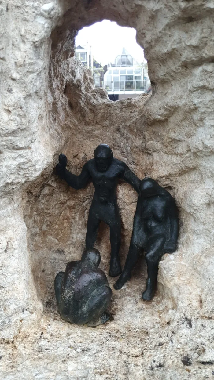 Een bronzen beeld van oermensen in een stenen nis