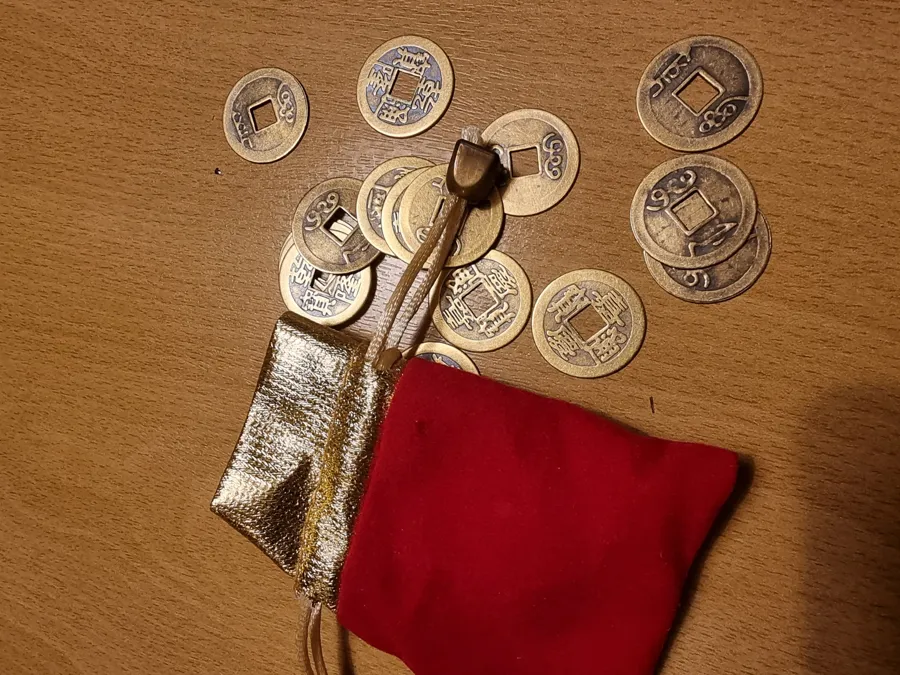 Oude munten met een vierkant gaatje en een rood zakje