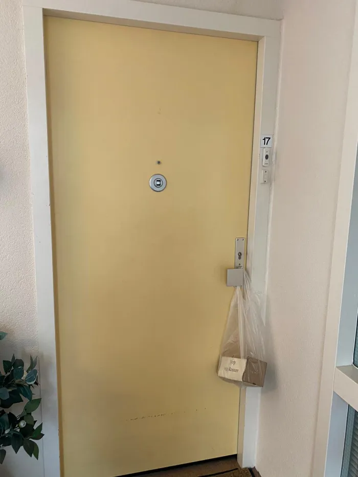 Een tasje met een kistje aan de klink van een voordeur
